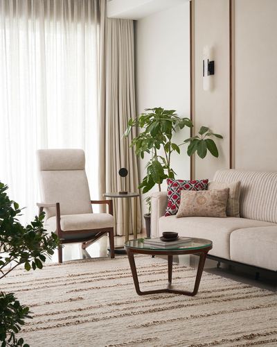 Beige living room with wooden armchair, round glass coffee table and striped rug