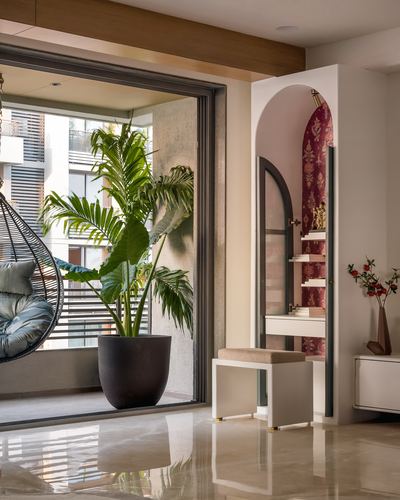 Foyer with arched maroon niche, marble floor, potted palm and glimpse of balcony swing