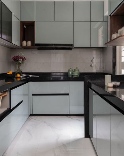 U-shaped kitchen with sage green glossy cabinets and black stone countertop
