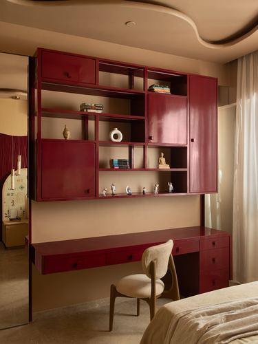 Burgundy lacquered shelving and built-in desk with cane-back chair in a Mumbai bedroom nook