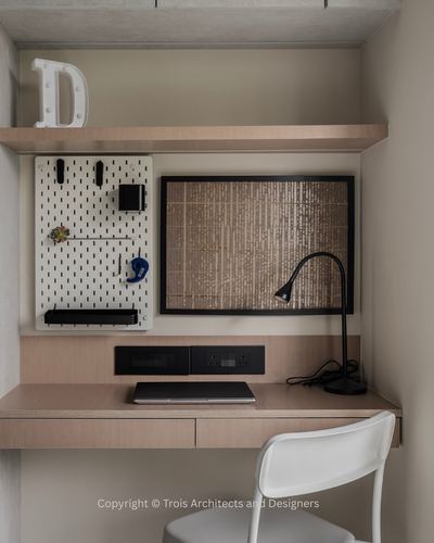 Built-in study nook with floating wood desk, pegboard, framed art, and white chair