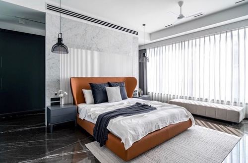 Bedroom with tan leather bed, marble headboard wall, and floor-to-ceiling sheer curtains
