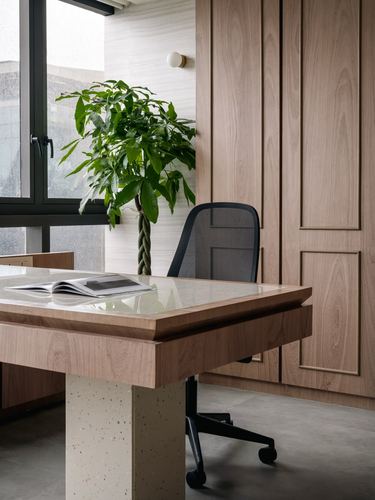 Corner office desk with terrazzo top, mesh chair, and plant against wood paneling