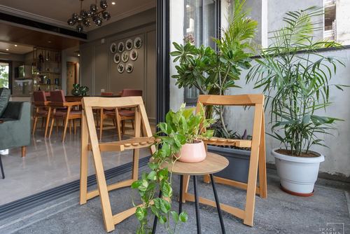 Balcony with wooden folding stools and potted plants opening into a dining room with terracotta chairs