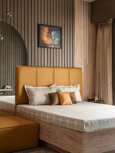 Bedroom with mustard leather headboard, wood-slat wall, tree painting, warm lighting