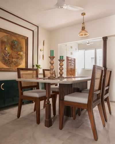 Dining table with cane-back chairs, framed painting, and pendant light in a warm-toned room