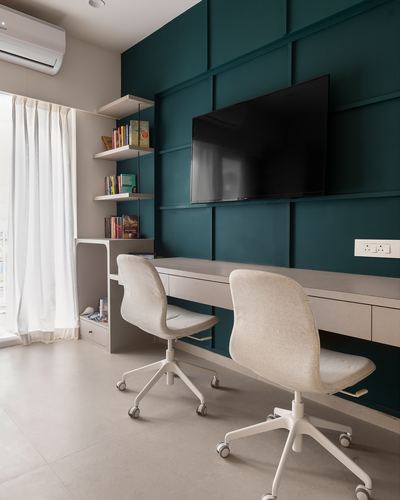 Study nook with teal paneled wall, wall-mounted TV, floating desk and two upholstered chairs