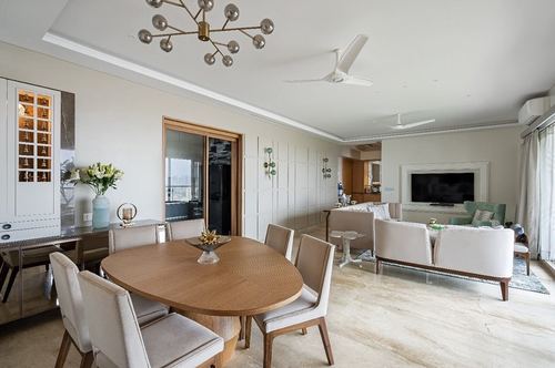Open-plan dining and living area with oval wood table, sputnik chandelier, and paneled accent wall