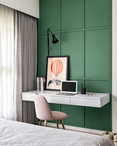 Floating white desk with pink velvet chair against green paneled wall study nook