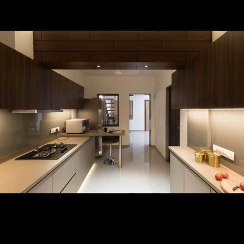 Galley kitchen with dark wood cabinetry, under-cabinet lighting, and view down corridor