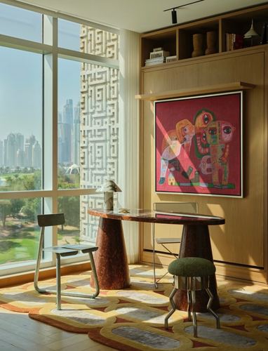 Sunlit corner nook with oval stone table, metal chairs, and colorful painting against city skyline