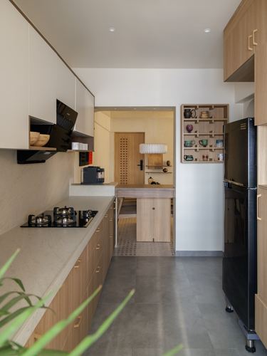 Narrow galley kitchen with wood cabinetry leading to a small foyer with a display shelf