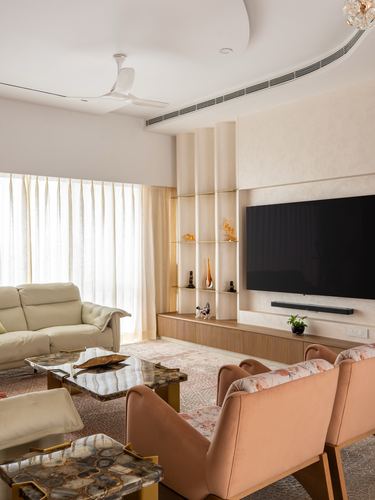 Living room with fluted cream panel niche, blush upholstered chairs, and stone coffee table