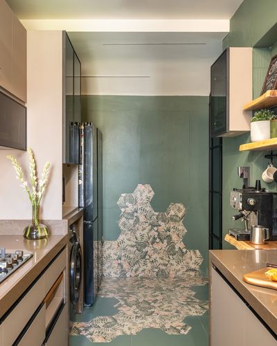 Galley kitchen with green ribbed walls and a floral hexagonal tile panel on floor and back wall.