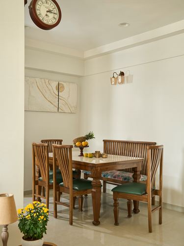 Wooden dining table with green leather chairs and bench under an abstract wall artwork