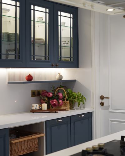 Navy blue glass-front kitchen cabinets above white countertop with floral styling and wicker basket