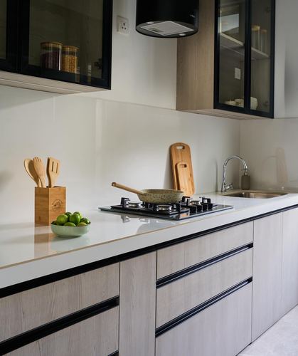 Modern kitchen counter with gas hob, sink, wooden utensil holder and glass-front cabinets