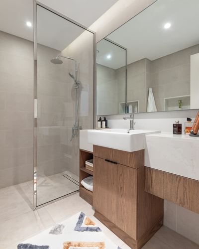 Modern bathroom with glass-enclosed shower, wood vanity, and large mirror above stone counter