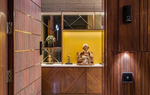 View through open wooden door into foyer niche displaying a Ganesh idol on a lit console