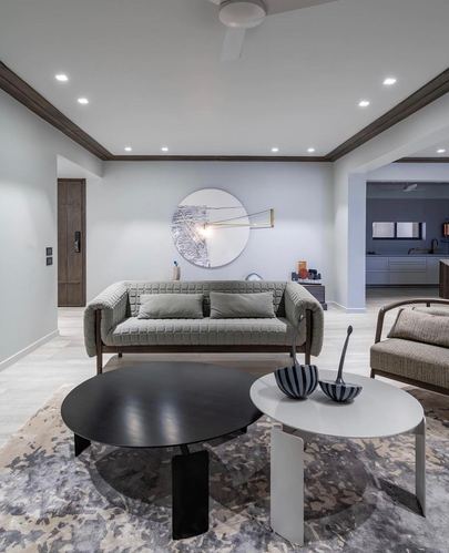 Grey living room with quilted sofa, round mirror, black and white nesting coffee tables on patterned rug