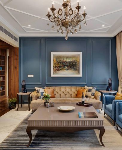 Formal living room with tufted beige sofa, blue panelled wall, and crystal chandelier