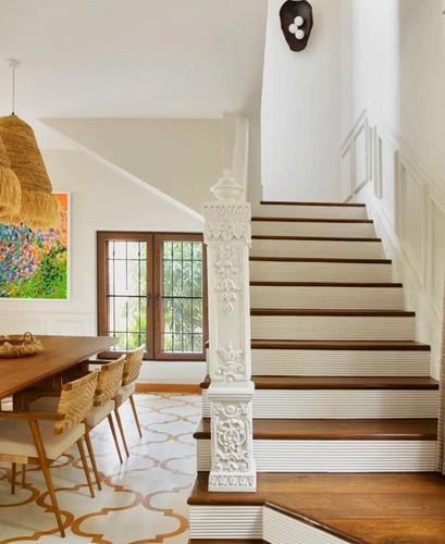 Staircase with carved white newel post beside dining area with patterned tile floor