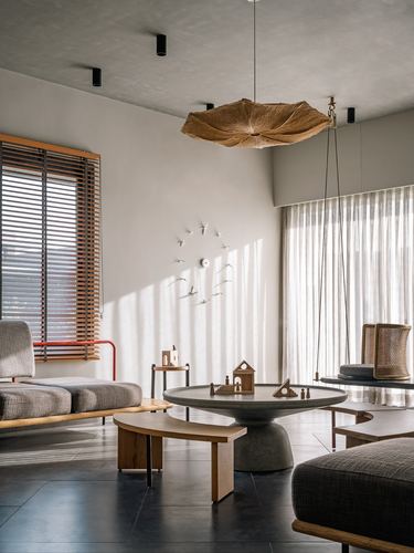 Sunlit living room with woven pendant, stone coffee table, and hanging cane swing