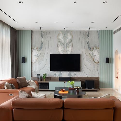 Living room with terracotta sectional facing marble TV wall flanked by fluted green panels