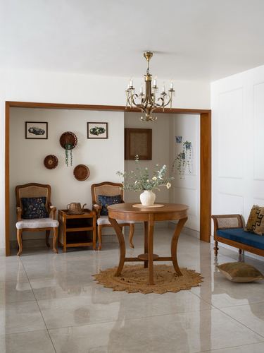 Foyer with round wooden table, chandelier, cane armchairs and woven wall baskets
