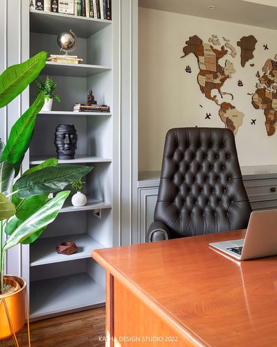 Home office with tufted leather chair, wooden desk, and wooden world map wall art