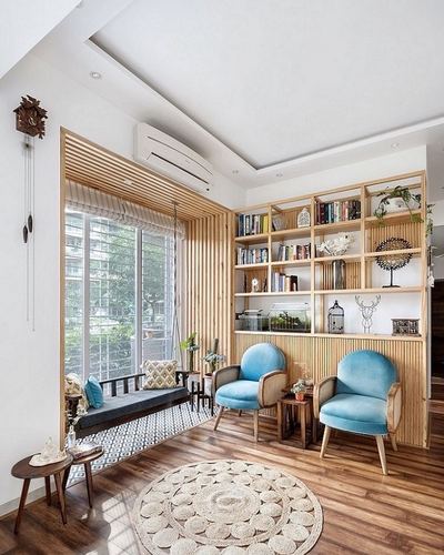Bright living room with fluted wood bookshelf, blue cane armchairs, jute rug and window seat
