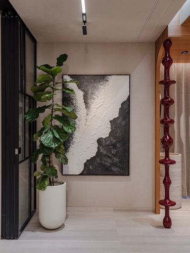 Foyer with fiddle leaf fig, textured black-white artwork, and red sculptural lamp beside wooden arch