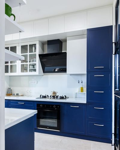 L-shaped kitchen with navy blue lower cabinets, white upper cabinets, and black chimney hood
