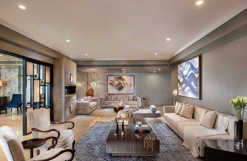 Grey and beige luxury living room with layered seating, marble coffee table, and blue abstract art