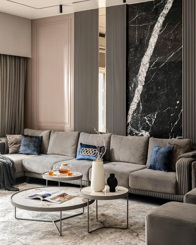 Grey sectional sofa facing round coffee tables against a marble and fluted panel wall