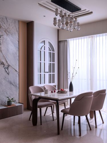 Dining room with marble feature wall, arched glass cabinet, and blush pink chairs around marble table