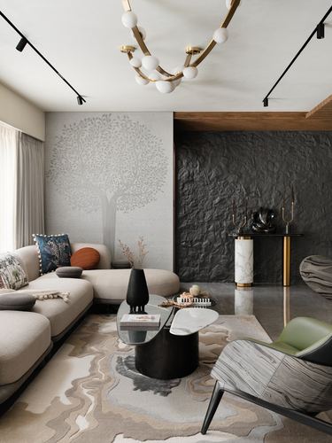 Living room with beige sectional, tree mural, textured black wall, and sculptural marble coffee tables