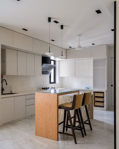 Modern kitchen with ribbed cabinetry, wooden island, stone waterfall edge and pendant lights