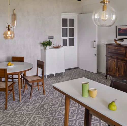 Dining area with patterned tile floor, wooden chairs, and glass pendant lights in Mumbai home