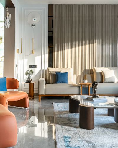 Living room with orange curved sofa, fluted paneled wall, and round marble coffee table