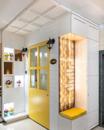 Foyer with mustard yellow glass-paneled door and backlit welcome nook with seating