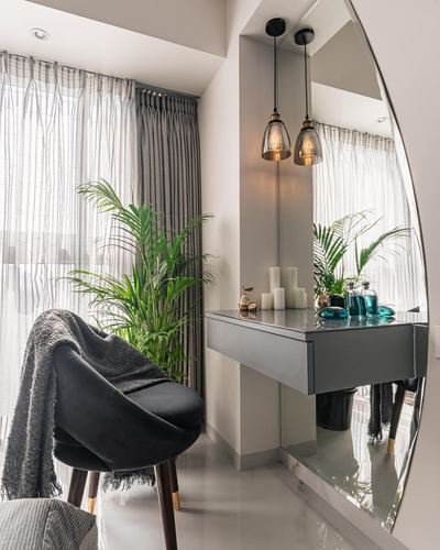Vanity nook with round mirror, floating stone console, pendant lights, black velvet chair by sheer-curtained window