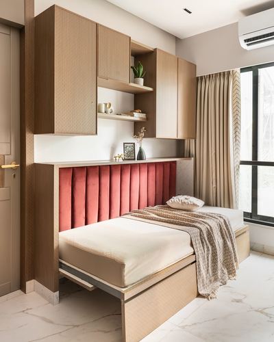Single bed with pink velvet channel headboard beneath wood cabinetry in a marble-floored bedroom