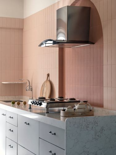 Pink tiled kitchen wall with arched niche, black hood, marble countertop and stove
