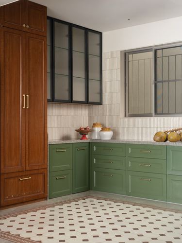 Kitchen corner with green cabinetry, wooden pantry, fluted glass cabinets, and patterned tile floor