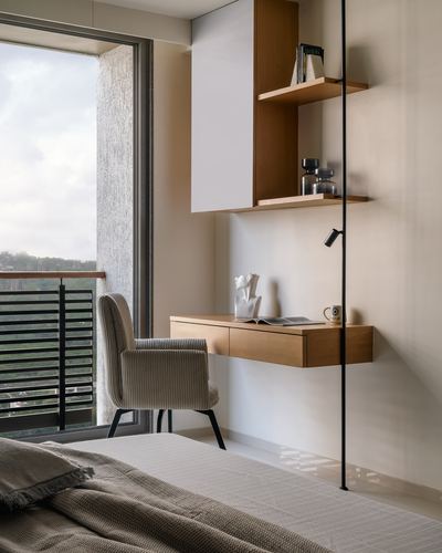 Bedroom corner with floating wood shelves, wall desk, corduroy chair, and balcony view