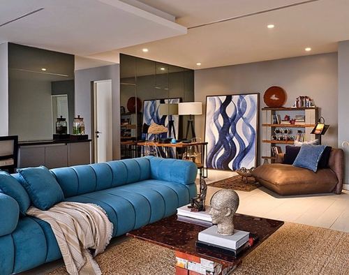 Living room with teal channel-tufted sofa, blue abstract art, and mirrored wall panel