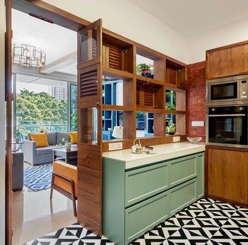 Kitchen with sage green cabinetry, wooden display shelving, and black-and-white geometric tile floor, opening to living room