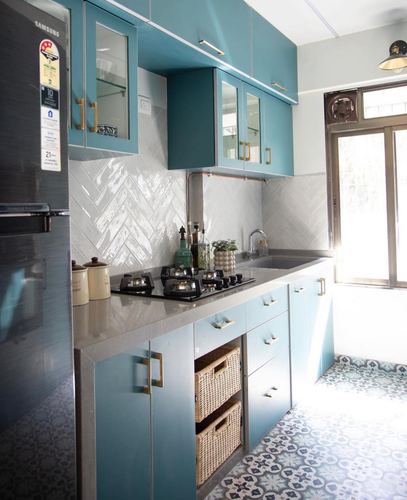Teal galley kitchen with herringbone backsplash, grey countertop, and patterned tile floor