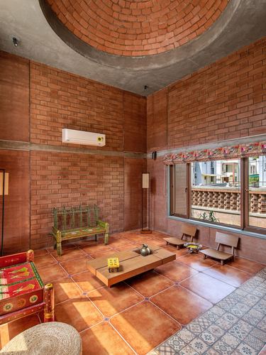 Brick-walled living room with domed ceiling, terracotta floor, and low wooden furniture